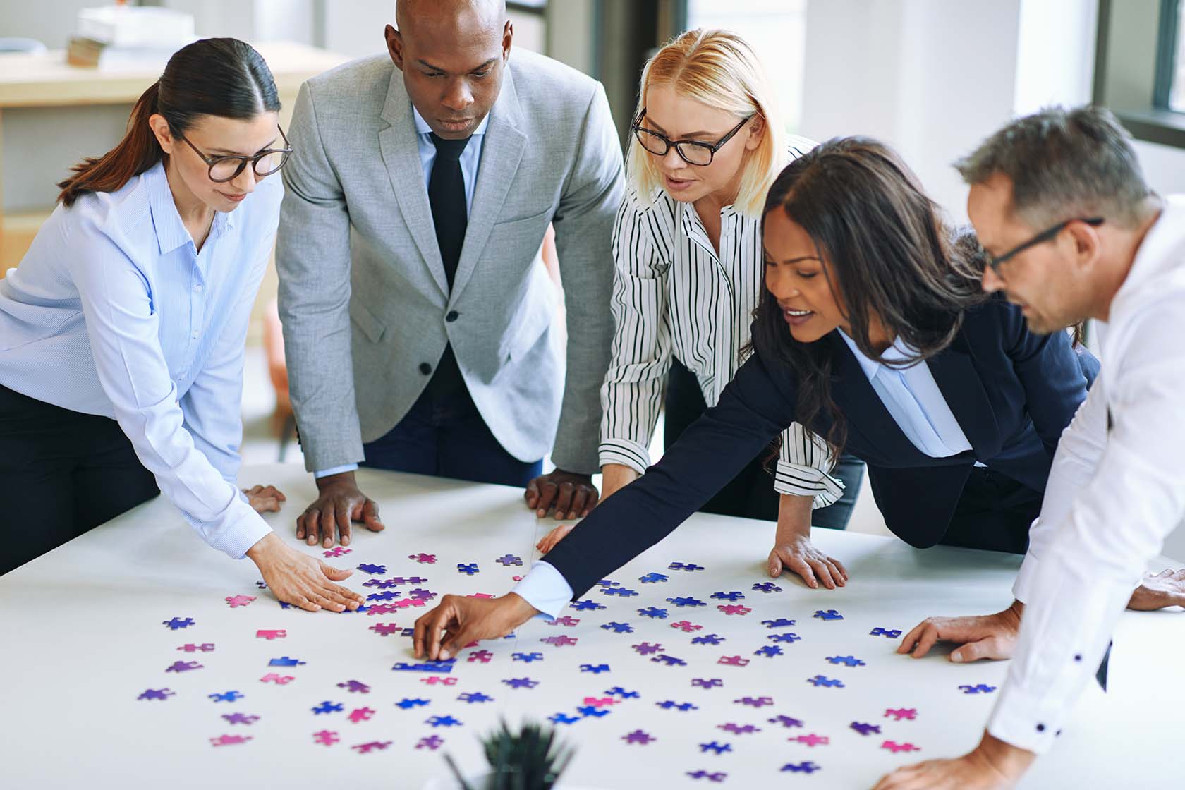 Diverse Team of Employees Working on a Puzzle in the Office to Build Teamwork